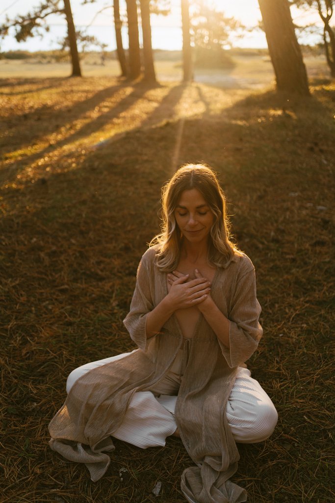 kvinna som sitter i lotusställning och mediterar i skogen